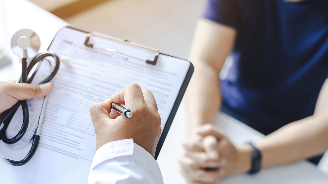 Provider with a clipboard and a patient in the background.